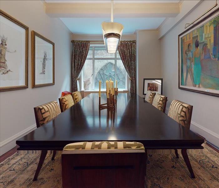 Dining room with an area rug, multiple paintings, a chandelier, a long dining table, and 8 upholstered chairs in front of a c