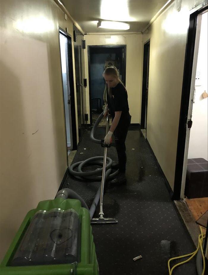 tech vacuuming wet corridor in building