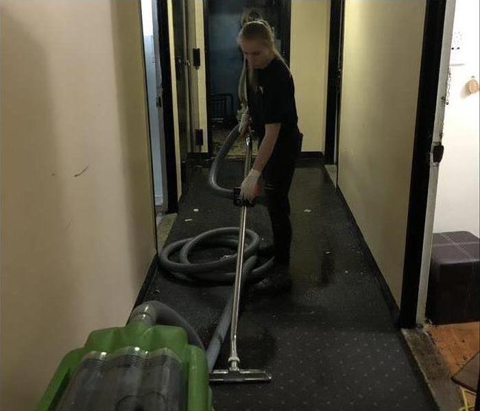 tech vacuuming wet corridor in building