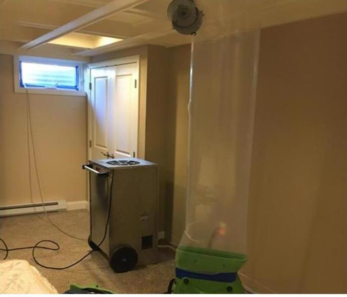 An air mover and lay-flay poly duct forcing warm air into a ceiling