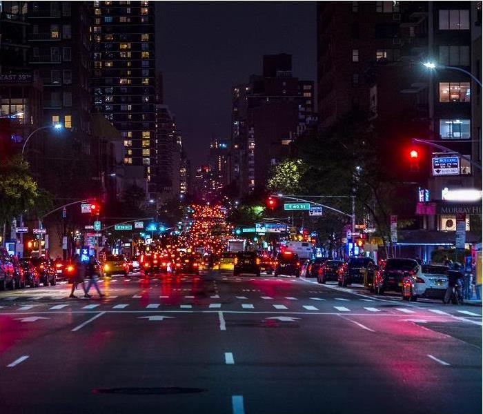 nighttime view of city street; busy street showing cars and people walking